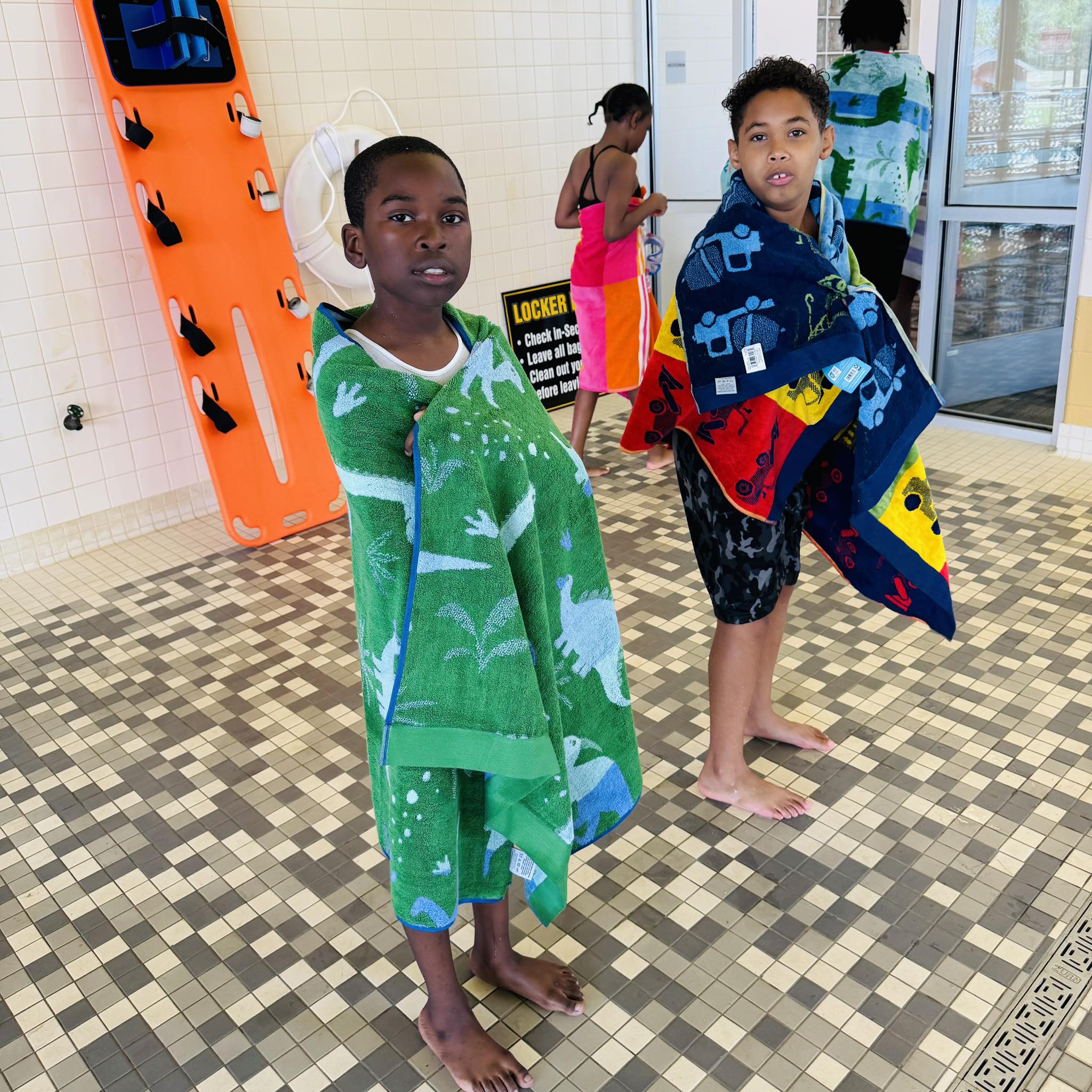 Two boys wrapped in beach towels.